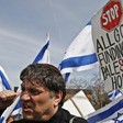 Meir Weinstein speaks as Israeli flags wave in background