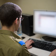 Man in military uniform sits in front of computer