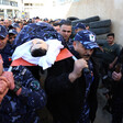 Men in camouflage uniform carry body on stretcher