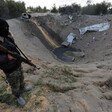 Masked man holding gun stands near sandy crater