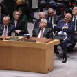 Several men, all in suits, sit behind a curved desk