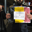 Man holds black, yellow and red placard 