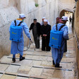 Men wearing protective clothing use backpack sprayers in alley