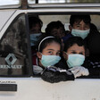 Children wearing face masks look out of vehicle window
