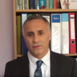 A man in a suit stands before a book shelf