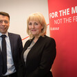 A woman and a man in suits pose and smile