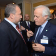 Two men talk together at conference with people in background