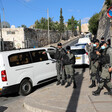 Armed soldiers in protective masks stand near vans