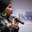 Woman holds microphone with one hand and gestures with the other