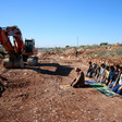 Men pray near construction equipment