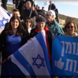 A group of people with Israeli flags and a banner in Hebrew