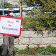 Man wears protective mask and holds sign