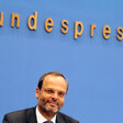 Smiling man sits a press podium