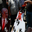 People hold images of regional leaders with foot prints on them