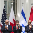 Three men clap in front of large flags 