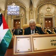 Mahmoud Abbas sits in a gold-themed room behind a sign with Palestine written on it