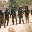 Several Israeli soldiers holding guns stand in a row