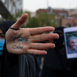 Woman holds hand up as others stand nearby with posters