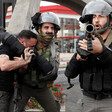 An Israeli police officer puts a Palestinian in a choke hold while another officer points a gun