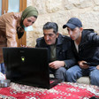 Two men and a woman stare at a laptop