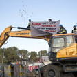 People on top of construction equipment hold banner