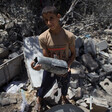 Boy holding metal object stands amid rubble