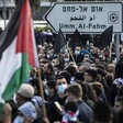 People demonstrate in large numbers, holding flags  