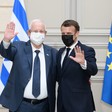Reuven Rivlin and Emmanuel Macron, both wearing face masks, wave while standing in front of Israeli and EU flags