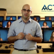 A man stands in front of a rows of desks with computer monitors