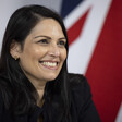 A woman smiles in front of a British flag