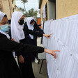 Women point to sheets of paper hung on notice boards