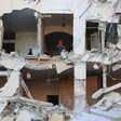 Women stand inside building with torn off facade