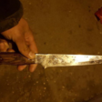 A hand holding a chef's knife with brown handle