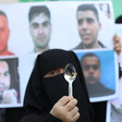 A woman standing by pictures of escaped men holds a spoon