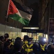 Protesters with a Palestinian flag facing police