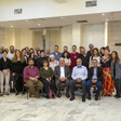 Group photo of people sitting on chairs and standing in conference room