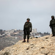 Men in combat gear stand on hilltop