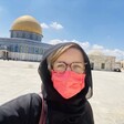 Woman in face mask stands in front of Jerusalem's Dome of the Rock