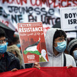 Two men wear masks while holding signs