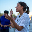 Woman speaks at microphone with onlookers behind her