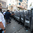A row of police officers wearing helmets and carrying shields 
