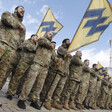 Men in military uniforms parade holding banners