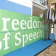 Two men stand next to banner reading freedom of speech