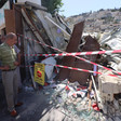 A man standing with arms akimbo looks at taped-off rubble 