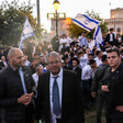 Three men stand in the front while others wave flags behind them 