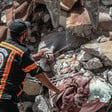 Civil defense worker touches arm protruding from under rubble