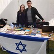 A woman and a man at a stall draped in an Israeli flag