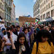 Large crowd walks down street with signs and flags