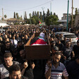 People carry a body wrapped in a flag in a coffin 