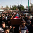 People carry a body wrapped in a flag in a coffin 